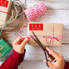 Woman wrapping a Christmas gift using a Christmas Gift Sticker